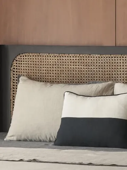 A detail shot of the custom black bed with a woven rattan headboard. The mix of black and natural cane creates a striking contrast that is both modern and timeless.
