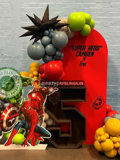 A powerful "Super Hero" setup for a fifth birthday, featuring the Avengers team. The bold red backdrop and a custom-built number '5' shelf for displaying treats make this a standout design.
