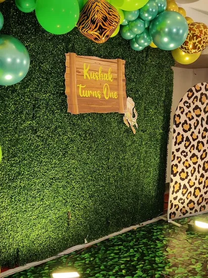 A close-up of a jungle-themed photo corner. The setup includes a green wall, a wooden sign, and a leopard-print arch, creating a perfect spot for pictures.