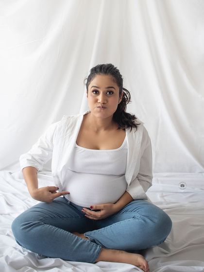 A cute and funny solo shot, with the mother-to-be playfully pointing at her bump. It shows the fun side of pregnancy.