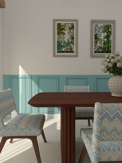 This dining area design uses chairs with a chevron pattern fabric that complements the wall art and the light blue wainscoting, creating a cohesive and stylish look.