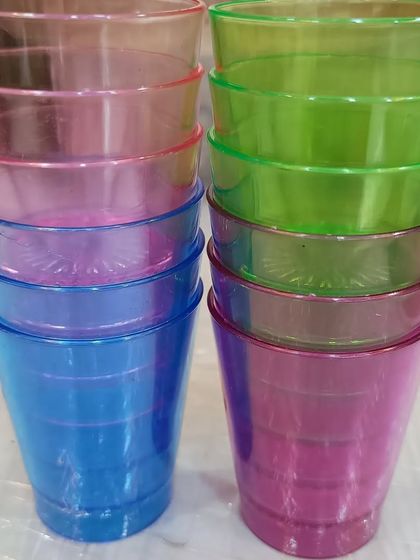 Colorful plastic shot glasses, perfect for parties. These reusable glasses come in bright shades of pink, green, and blue, adding a pop of color to your drink station.