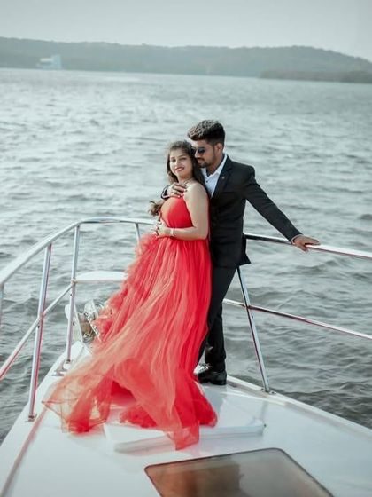 A beautiful shot of a couple on a yacht, with the red gown flowing in the wind. It captures a sense of freedom and romance.