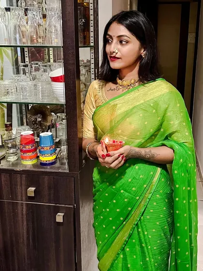 Celebrating Diwali in a vibrant green and gold polka-dot saree. This traditional look, complete with a gold necklace and nose ring, captures the festive spirit of the occasion.