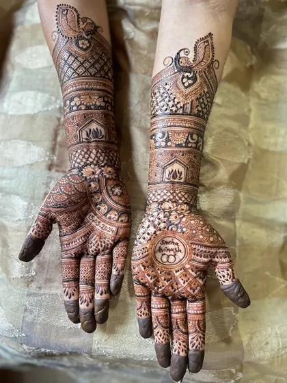A beautiful engagement mehendi with traditional peacock armlets and circular mandala designs on the palms that include the couple's initials.