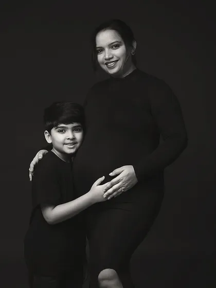 A timeless black and white portrait of a mother and her son. His arm around her, and her hand on her belly, tells a story of love, protection, and new beginnings.