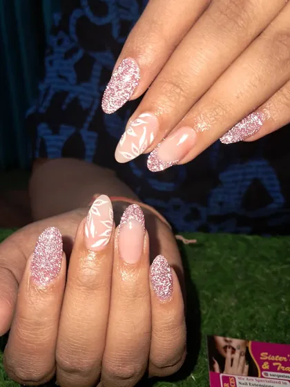A lovely design combining sparkling pink glitter nails with accent nails that have a delicate, hand-painted white leaf pattern.