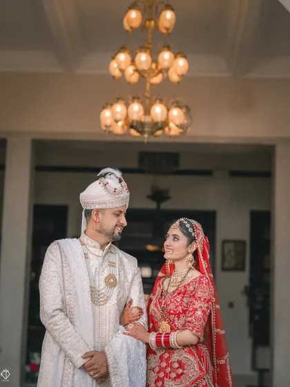 The couple sharing a sweet glance under a grand chandelier, a classic portrait from their wedding day.