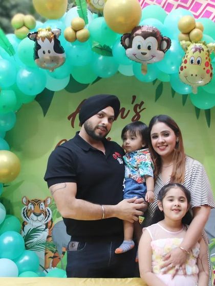 A family of four at a jungle-themed birthday party. We capture the whole family, including siblings, in front of the festive animal-themed balloon decor.