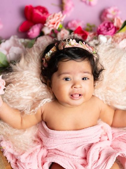 A beautiful three-month milestone portrait. This baby girl, surrounded by a bed of pink flowers, looks like a little blossom herself.