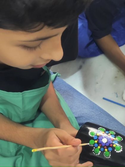 A close-up shot of a young boy carefully applying dots to his mug, completely absorbed in the creative process.