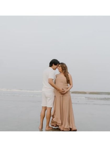 An intimate embrace with the vast ocean behind them. This image captures the feeling of it being just the two of them against the world, waiting for their little one.