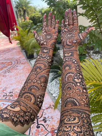A beautiful shot of full-sleeve mehandi against a natural backdrop. The design is filled with intricate mandalas and traditional patterns.