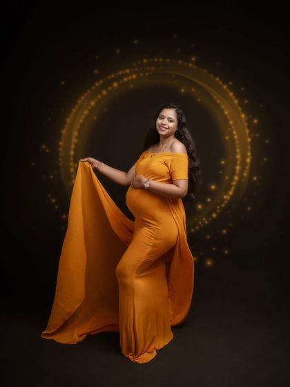 Glowing like the golden hour. This stunning mumma shines bright in a custom golden gown against a dark green backdrop with a sparkly sphere.