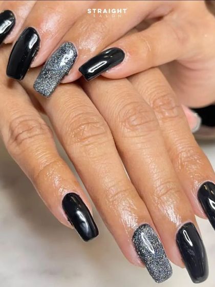A bold and glamorous look featuring long, square-shaped nails in a jet black polish with sparkling silver glitter accent nails.