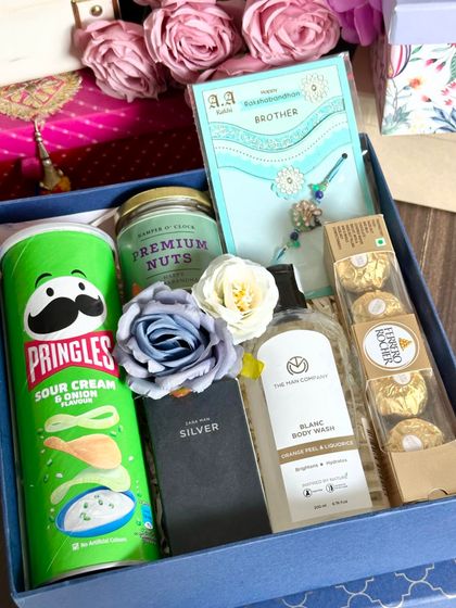A fun Rakhi hamper for your brother, featuring Pringles, a jar of premium nuts, a Zara mini perfume, a Man Company shower gel, and Ferrero Rocher.