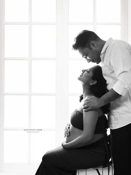 An intimate black and white couple's portrait. The high-contrast window lighting creates a romantic and timeless feel, focusing on their connection.
