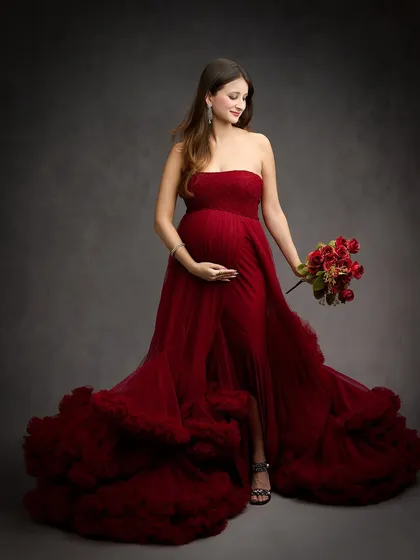 This portrait is all about glamour and confidence. The voluminous, ruffled red gown and classic studio lighting come together to create a striking, high-fashion maternity photograph that makes a bold statement.