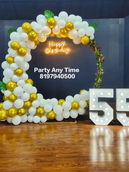 A clean and simple 55th birthday decoration with a circular balloon arch and large light-up numbers.