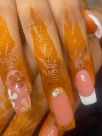 A close-up of the detailed floral nail art and rhinestone accents that complement the French tips.
