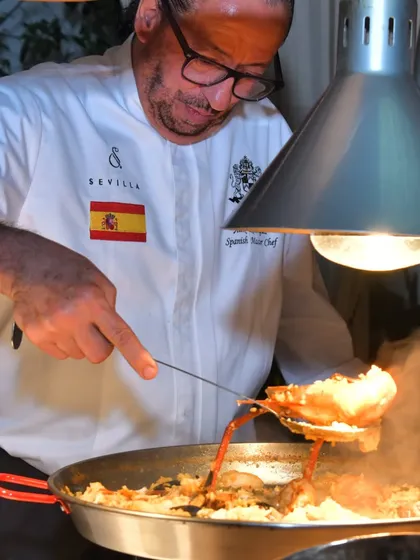 The art of paella making requires constant attention. Here, I am tending to a large pan of paella, ensuring the rice cooks evenly and absorbs all the rich flavors.