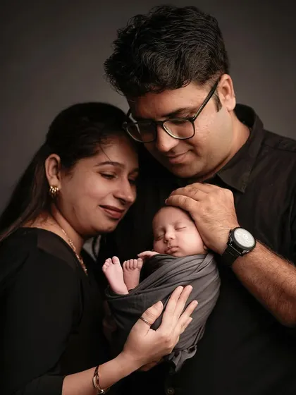 The world in their hands. New parents gaze lovingly at their sleeping newborn, a classic and powerful pose that encapsulates the overwhelming love of welcoming a new life.