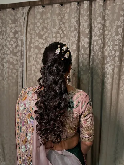 A chic and modern ponytail with curls, adorned with leafy hair accessories.