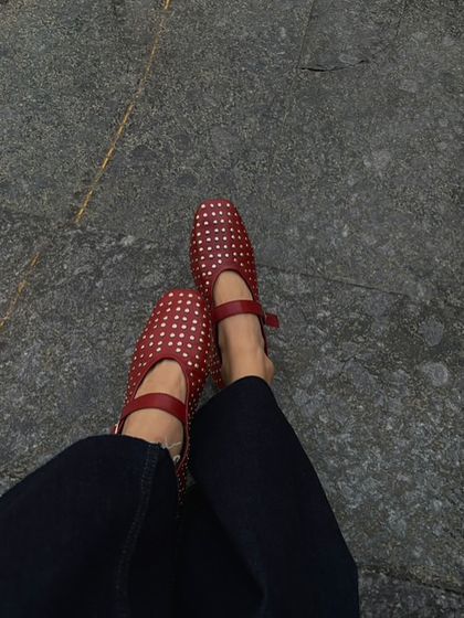 A customer styling our red studded ballet flats for a winter brunch. The pop of red adds warmth and personality to her dark denim, showing how a great shoe can elevate a simple outfit.
