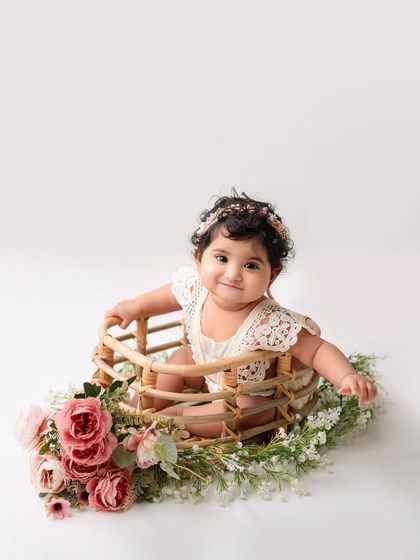 A close-up of a baby girl in a basket decorated with flowers.