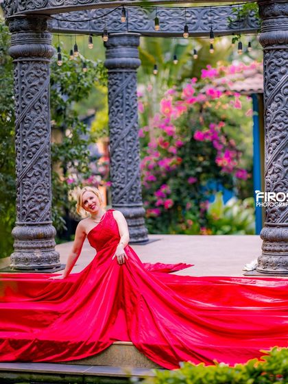 A model poses with a flowing red dress at our stone gazebo, creating a stunning and vibrant image.