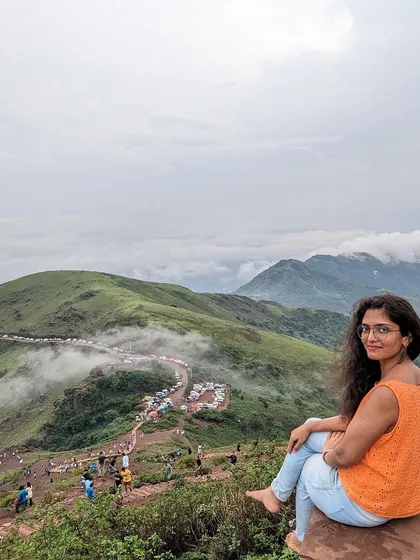 A traveler sitting on a peak in Chikmagalur, enjoying the stunning view of the Western Ghats.