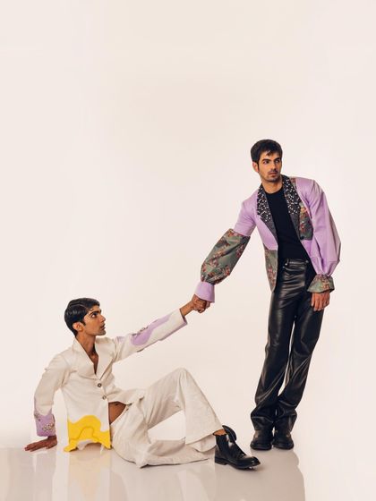 A connected pose from the "Monsieur" editorial, showcasing the relationship between the two distinct outfits. The styling emphasizes both individuality and cohesion within the collection.