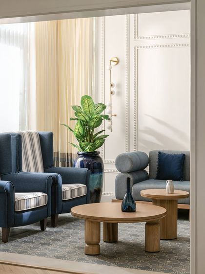 This sunroom is designed for slow mornings, with custom-upholstered wingback chairs in navy and stripes. We paired them with sculptural oak coffee tables to bring in organic warmth and create a timeless coastal feel.