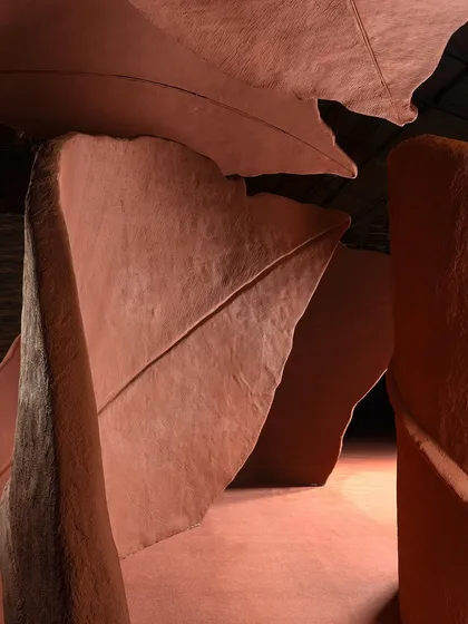 The powerful, curving forms of the 'Terra' installation seen from a low angle. The dramatic lighting and deep shadows accentuate the sculptural quality of the giant leaves.