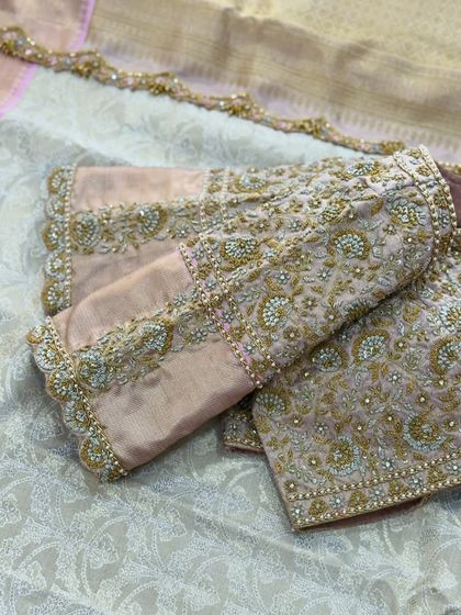 A peach blouse with all-over floral embroidery in gold and pearl.