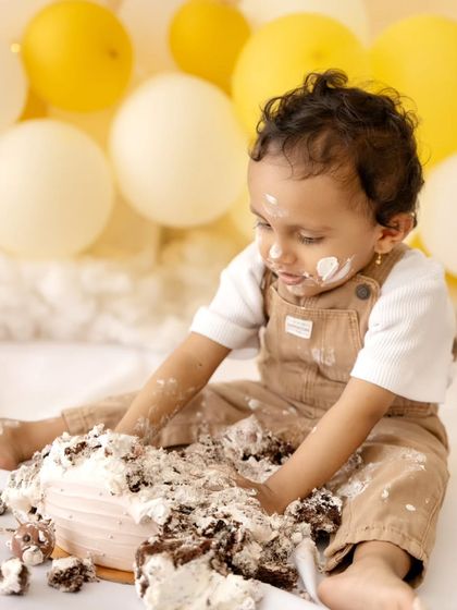 A close-up shot focusing on the baby's hands deep in the cake, a testament to a successful and enjoyable smash session.