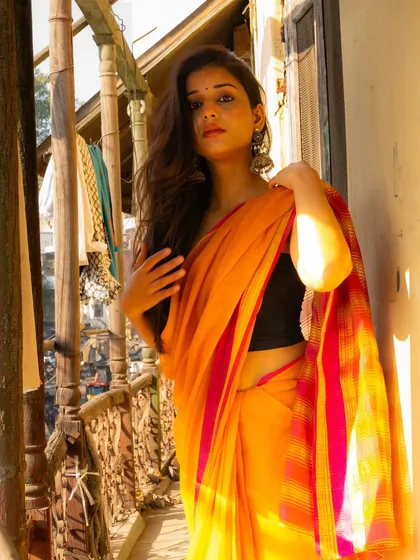 A confident portrait on the balcony, with the warm sunlight highlighting the colors of the saree and the model's features.