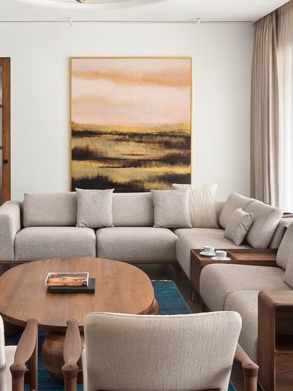 The main living area of the West Coast Residence, featuring a large L-shaped sofa, a custom oval coffee table, and a large landscape painting that brings a sense of calm to the room.