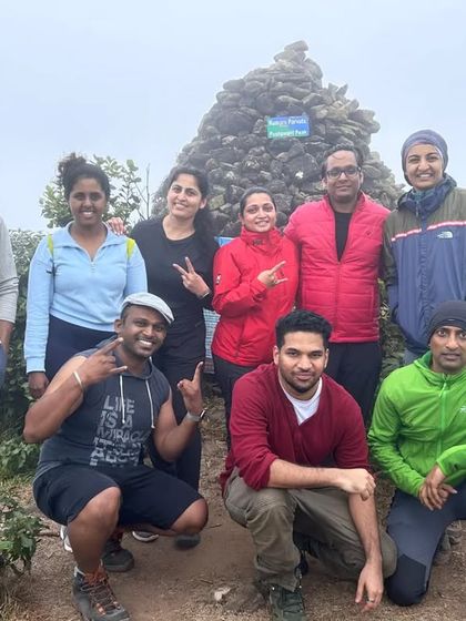 A group posing at a stone cairn on the Kumaraparvatha trail, marking a milestone on their journey.