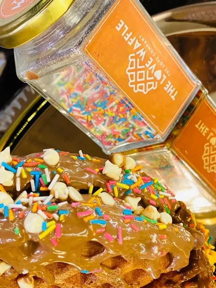 A close-up of the sprinkle-covered waffle, showing the generous toppings and crunchy white chocolate chips.