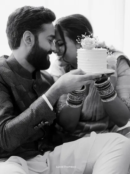 A tender black and white moment with a wedding cake, the focus on the couple's gentle interaction rather than the object.