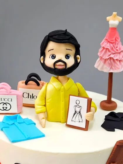 A close-up of the fashion stylist figurine, holding a sketchpad. It's the small, personalized details that truly capture the essence of the person we're celebrating.