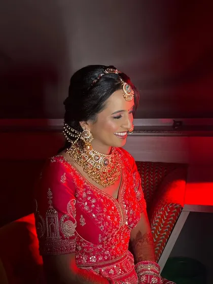 The red lighting adds a dramatic flair to this shot, but the bride's makeup remains impeccable. The highlighter catches the light beautifully, and her smile is infectious.