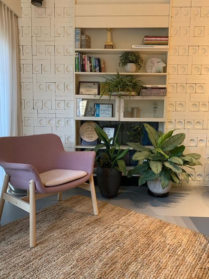 A corner of my studio, featuring a repurposed bookshelf and a textured wall made of concrete blocks. This reading nook showcases my belief in sustainable design and the power of biophilia, with plants adding life to the space.