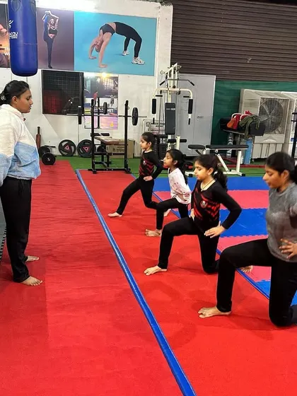 A coach leads a group of young girls through a lunge exercise. We teach proper form for fundamental fitness movements to build a strong athletic base.
