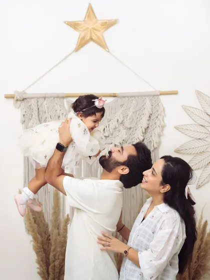 A candid and joyful moment of a young family in the studio. The father lifts his daughter, creating a memory filled with laughter and love, showcasing a natural family portrait session.