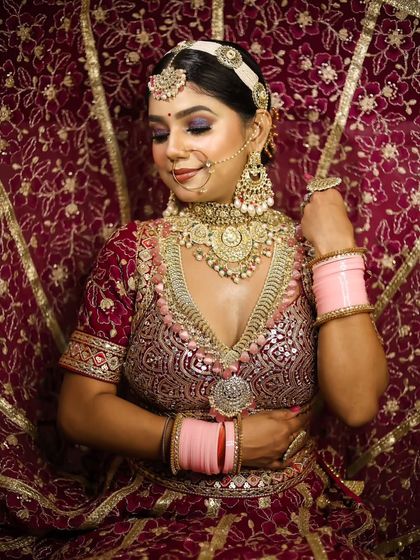 The bride's pose showcases the intricate embroidery of the lehenga, which the makeup beautifully complements.
