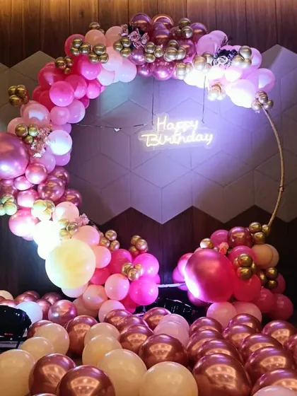 A beautiful rose gold and pink balloon ring decoration. The floor covered in balloons adds a fun, immersive element to the photo corner.