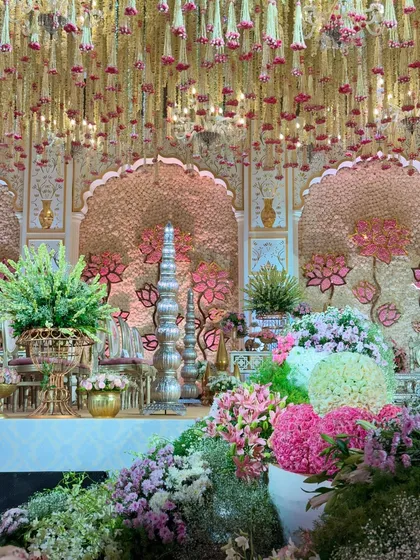 A detailed shot of the side of the stage, where silver and gold traditional decor pieces are nestled amongst a profusion of pastel flowers. It's a fairytale brought to life. ✨