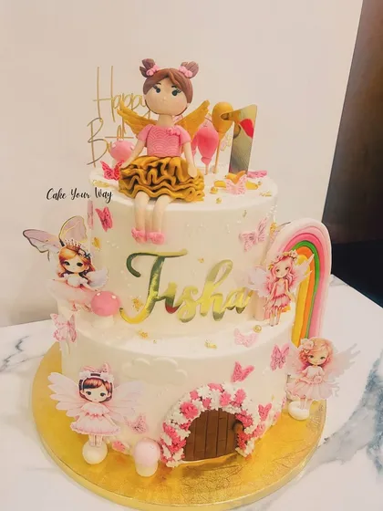 A whimsical two-tier fairy cake for Tisha's first birthday, with a fondant fairy, a rainbow, and a magical door.